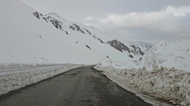A twisting snow-covered mountain road bordered by high snow walls, winding through snowy hills and rugged peaks under a cold, overcast winter sky.
📍Hawraman Takht, Kurdistan 