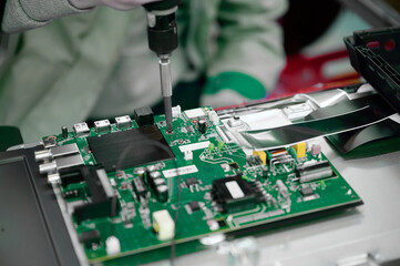 Obraz premium Workers assemble a circuit board at a television manufacturing plant focusing on precision and quality control
