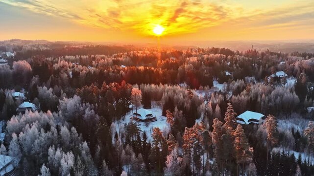 Isolated village in snowy boreal forest of Latvia at sunset. Aerial
