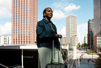 Businesswoman leaving international airport with rolling luggage