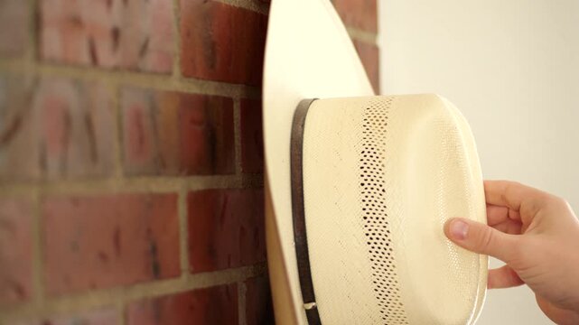 Person hanging cowboy hat on hook
