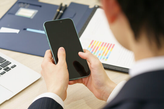 スマホを手にする若い男性の手元のアップ