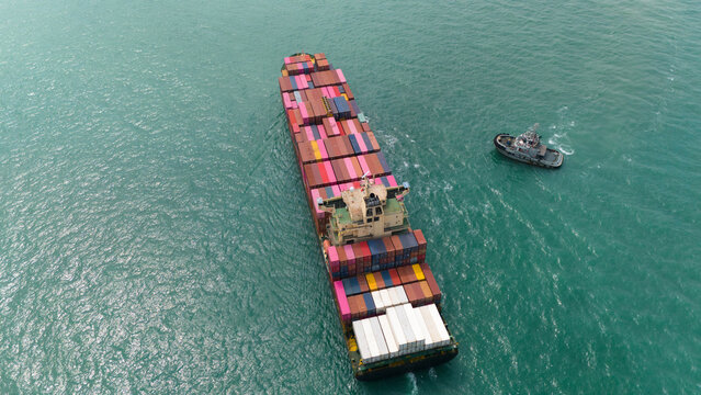 Aerial top view over international containers cargo ship at industrial import-export port prepare to load containers with big container loader ship vessel. global transportation and logistic business.