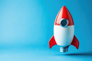 A shiny red and white toy rocket stands upright on a vibrant blue background with hard shadows
