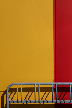 Bicycle rack casting shadows against vibrant yellow and red geometric color block wall