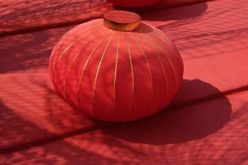 Traditional red lantern with gold trim casting shadows on a textured red surface