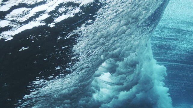 Underwater wave face with rippling surface patterns and clear blue tropical water texture