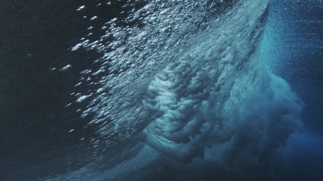 Moody underwater wave wall with drifting bubbles and soft light in deep blue ocean