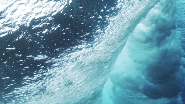 Powerful underwater wave face curling with bright turquoise light and textured motion