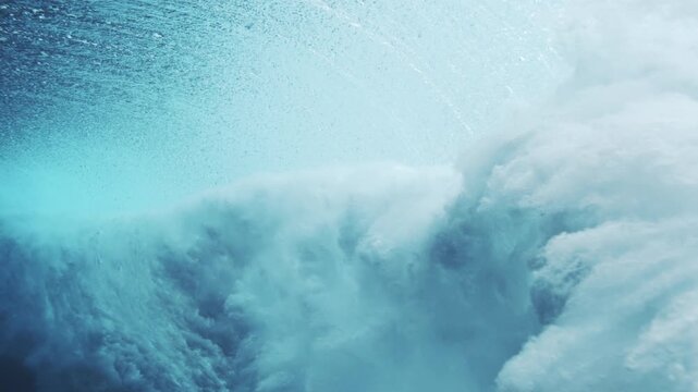 Bright underwater wave collapse glowing with turquoise light and foamy ocean texture