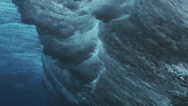 Dark underwater wave wall with layered textures and drifting bubbles in deep ocean water