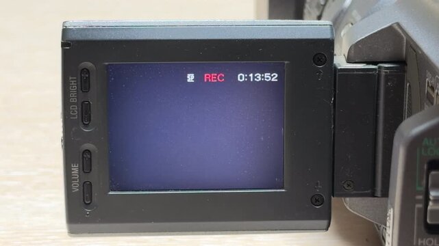 A vintage 3CCD camcorder begins capturing video, showing a red "REC" indicator on its screen. This action triggers a quick, high-pitched electronic beep to confirm the recording has started.
