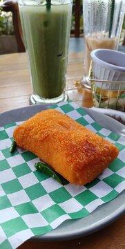 Fried risoles and green drink on table