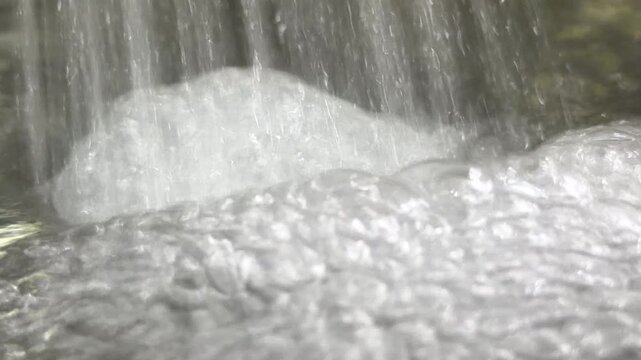 A powerful stream of water pours from a faucet into a metal pot. The heavy flow creates white foam and bubbles, resulting in loud rushing and flushing sounds.