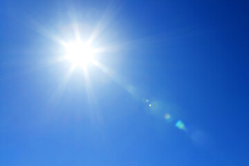 快晴の青空に輝く力強い太陽とレンズフレア。希望やエネルギーを象徴するクリーンな夏の空の背景素材 © Sa