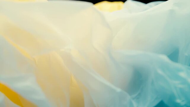 Light drapery of sheer fabric folding into soft waves and ripples, a turquoise to gold gradient catching ethereal light for an elegant, flowing abstract textile background