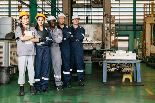 Group of professional success workers in safety uniforms stand together in heavy industry factory.