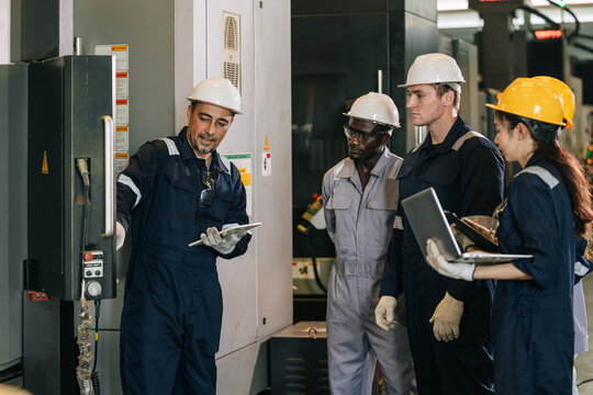 Professional senior engineer man training young engineer team to control operate machine in factory