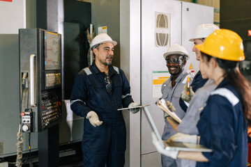 Professional senior engineer man training young engineer team to control operate machine in factory