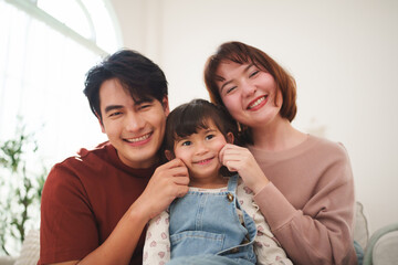Happy Asian parents and daughter smiling together at home family portrait