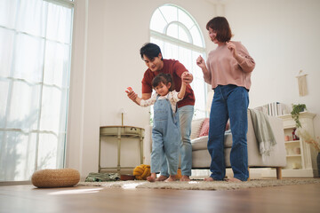 Happy Asian family dancing together in living room at home