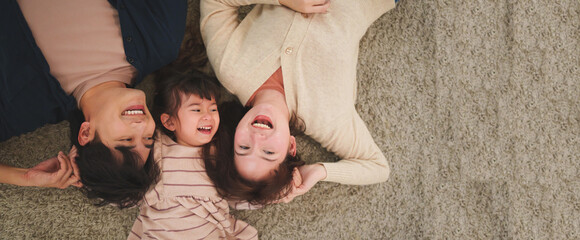 Happy Asian family hugging and laughing together on carpet at home