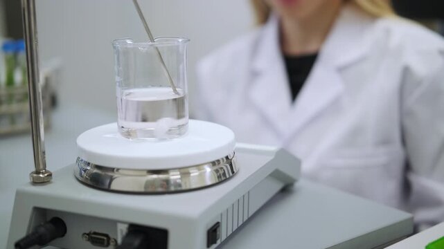 Female researcher monitoring solution mixing on magnetic stirrer. Laboratory chemistry, phytochemical extraction and scientific experiment concept.