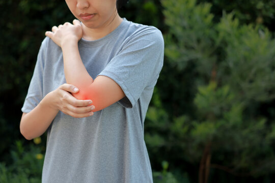 Young woman suffering from acute elbow pain and joint inflammation with red highlight effect, female touching sore arm, tendonitis, sports injury, arthritis, health problem, copy space background.