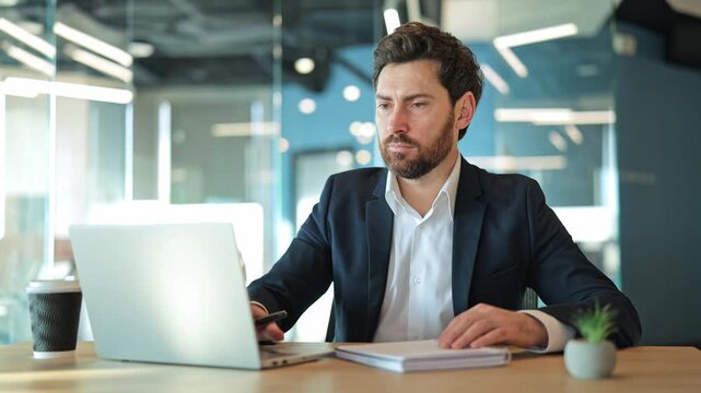 Professional working in contemporary office setting, demonstrating diligence and concentration while utilizing modern technology and traditional note taking. Productivity, and an earnest work ethic.