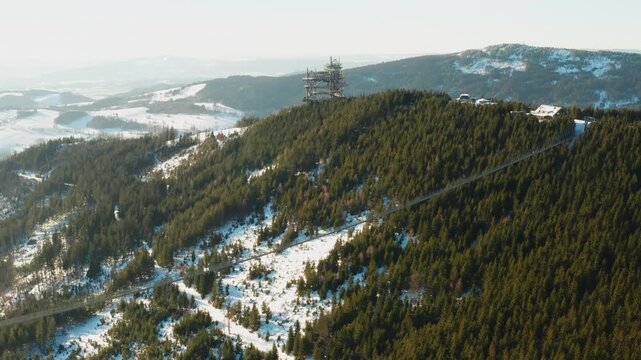 Aerial view of Sky Bridge 721 and Sky Walk observation tower surrounded by forest and mountains.