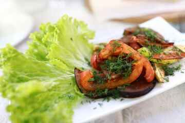 Cooked vegetable meal with lettuce leaves on white plate