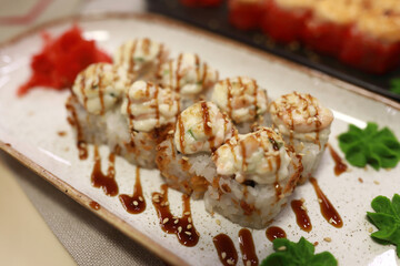 Delicious baked sushi roll with sauce on plate