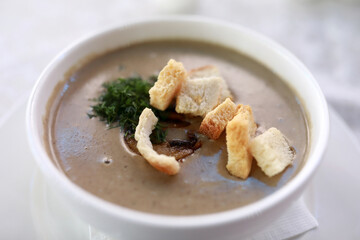 Creamy mushroom soup with croutons and dill in white bowl