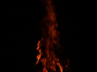 Close-up shot of a tall, fiery blaze with orange flames against a dark background.