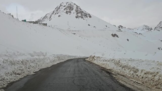 A snow-covered mountain road bordered by tall snowbanks, leading toward rugged snowy peaks under a cold, overcast winter sky.
📍Hawraman Takht, Kurdistan 