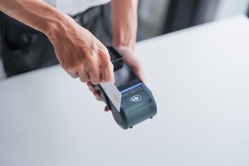 Asian Small Business Owner Swiping Credit Card on EDC Machine at Counter, Processing Secure Payment...