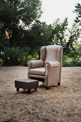 Fototapeta premium Beige armchair with matching footstool placed in nature outdoors