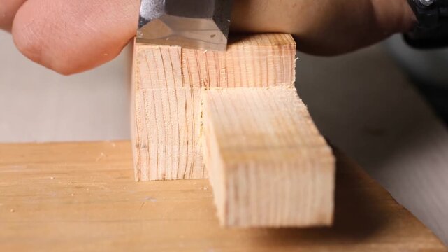A skilled woodworker uses a chisel to refine square mortise joints