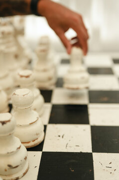 Person's hand moving chess piece on vintage board