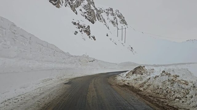 winding snow-covered mountain road with high snow walls, rugged snowy peaks and overcast sky in a remote high-altitude winter landscape.  
📍Hawraman Takht, Kurdistan 