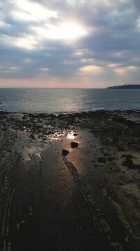 Drone view sunset at Tanjung Layar, an iconic tourist destination on Sawarna Beach, Banten, Indonesia, reflects beauty, serenity, and peace.