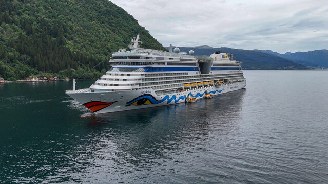 30 july 2025, Vik i Sogn, Norway. Aerial, bird view Aida diva cruise ship lying in the fjord of Vik I Sogn. High angle view of ship, surrounding mountains, nature in background. Cloudy day. Mass touri