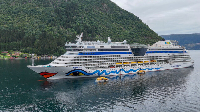30 july 2025, Vik i Sogn, Norway. Aerial, bird view Aida diva cruise ship lying in the fjord of Vik I Sogn. High angle view of ship, surrounding mountains, nature in background. Cloudy day. Mass touri