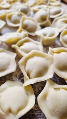 Top view of raw homemade dumplings pelmeni on a wooden board with flour.