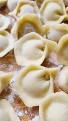 Top view of raw homemade dumplings pelmeni on a wooden board with flour.