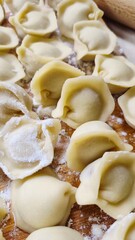 Top view of raw homemade dumplings pelmeni on a wooden board with flour.