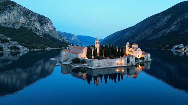 Tranquil Island Monastery in Serene Bay: Illuminated Buildings Reflecting in Calm Blue Water at Dusk