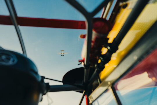 Seated inside a cockpit as a plane flies overhead at sunset.