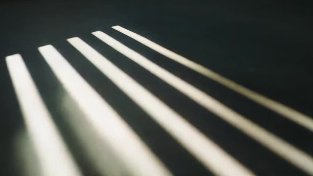 Sunlight beams streaming through window blinds. Casting a diagonal pattern of parallel light stripes and contrasting shadows on a dark surface. Creating an abstract and textured background