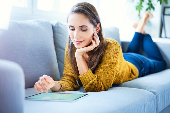 Young oman lying on sofa and using tablet